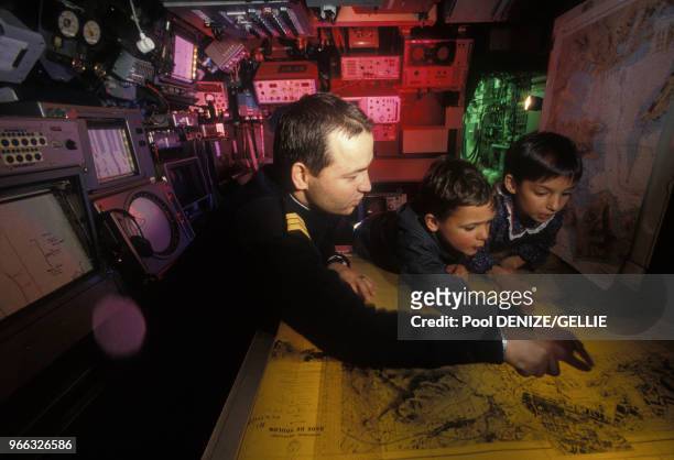 Enfants observant une carte marine dans la salle de contrôle du sous-marin Casabianca de la Marine française, le 27 février 1988, France.