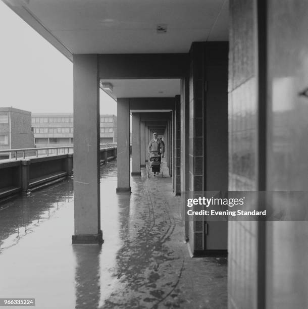 Woman pushes a pram down a portico passage at Aylesbury Estate Walworth, Southwark, London, UK, 14th February 1979.