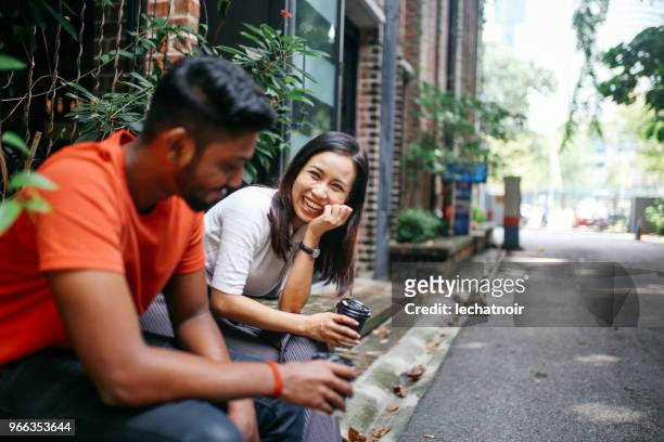 friends chatting outdoors in kuala lumpur, malaysia - asian discuss stock pictures, royalty-free photos & images