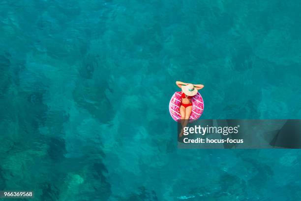 woman swimming with pool float in turquoise sea - air bed stock pictures, royalty-free photos & images