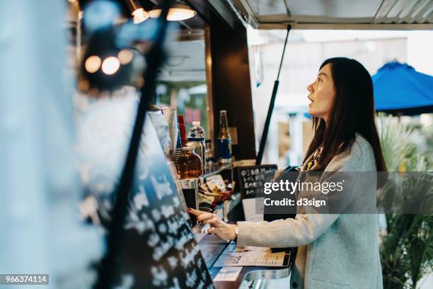 young woman ordering food and drinks from food truck - demanding ストックフォトと画像