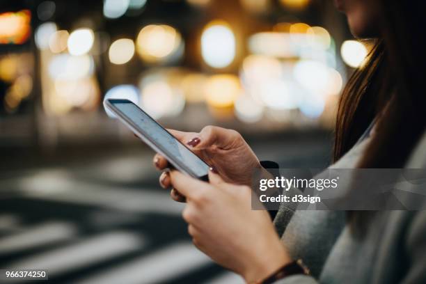 close up of woman navigating location with smartphone in busy city street at night - scrolling - fotografias e filmes do acervo