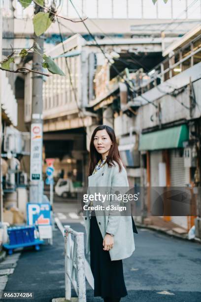 beautiful young woman looking over shoulder with smile whilst strolling in city - business people representative smile spontaneous stock-fotos und bilder