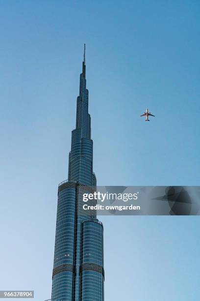 the airplane flying over burj khalifa tower in dubai - dubai fountain stock pictures, royalty-free photos & images