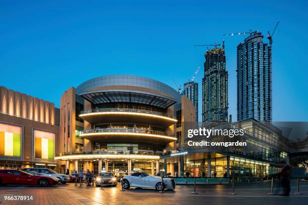 dubai mall building and neighboring skyscrapers reflected in the fountain at night - dubai mall stock pictures, royalty-free photos & images