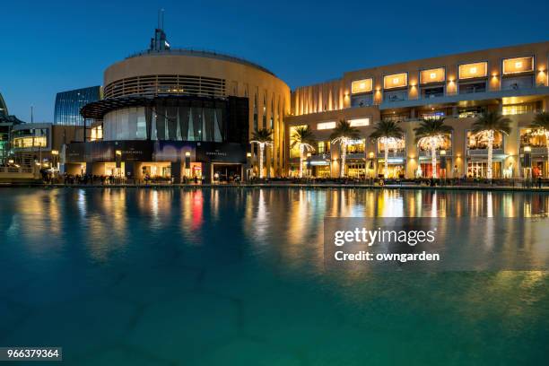 dubai mall building and neighboring skyscrapers reflected in the fountain at night - dubai fountain stock pictures, royalty-free photos & images