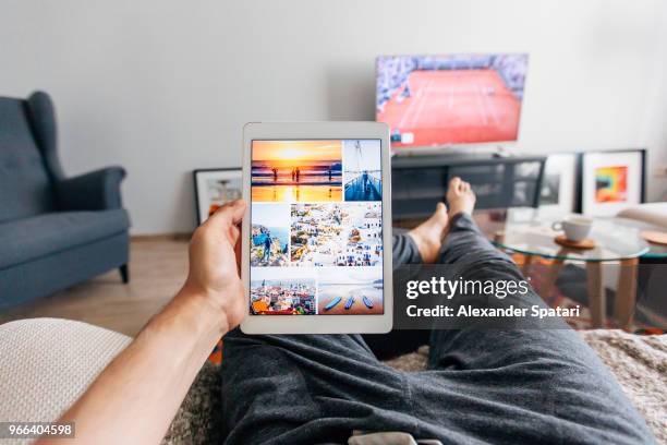 man relaxing on the sofa in apartment and using digital tablet, personal perspective - tablet screen home stock-fotos und bilder