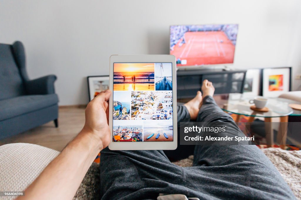 Man relaxing on the sofa in apartment and using digital tablet, personal perspective