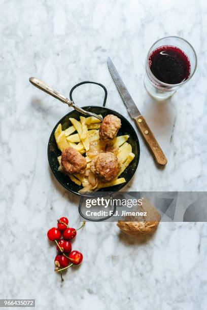 plate with meatballs and french fries next to red wine and cherries - covered food with wine stock pictures, royalty-free photos & images