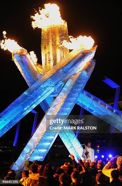 Ice hockey legend Wayne Gretzky holds the Olympic flame after lighting the cauldron during the 2010 Winter Olympic opening ceremony in downtown...