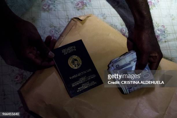Man holds a Ghanaian passport and a roll of Ghanaian cedi currency in Dormaa-Ahenkro on May 3, 2018. - Ghana's economy is expected to grow by 8.3...