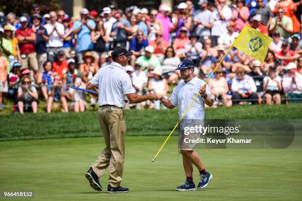 Matt Kuchar celebrates and bumps fists with his caddie John Wood after making a birdie putt on the 18th hole green during the third round of the...