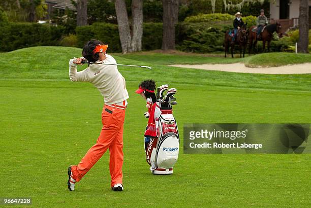 Ryo Ishikawa of Japan makes an approach shot on the 13th fairway as two people ride their horses in the background during a practice round for the...