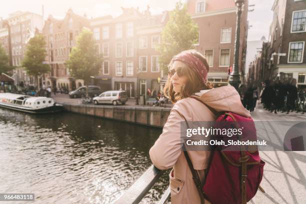 woman walking near canal in amsterdam at sunset - amsterdam spring stock pictures, royalty-free photos & images