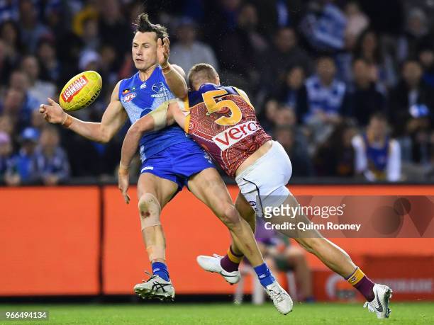 Ben Jacobs of the Kangaroos is tackled by Mitch Robinson of the Lions during the round 11 AFL match between the North Melbourne Kangaroos and the...