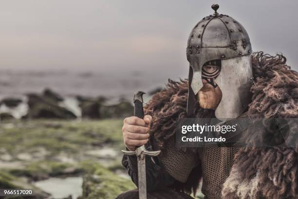 guerrero sangriento medieval esgrimiendo solos en una orilla del mar frío de la arma - viking warrior fotografías e imágenes de stock