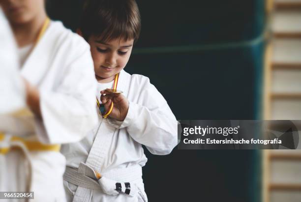 photograph of a little boy looking happy at a medal won practicing karate - judo 個照片及圖片檔