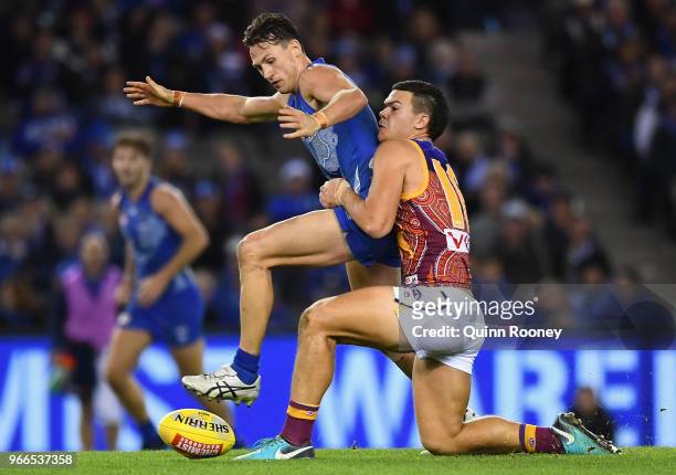 Ben Jacobs of the Kangaroos is tackled by Cameron Rayner of the Lions during the round 11 AFL match between the North Melbourne Kangaroos and the...
