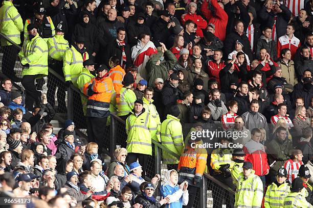 Police officers and stewards stand in between Portsmouth and Southampton fans during the FA Cup sponsored by E.ON fifth round match between...