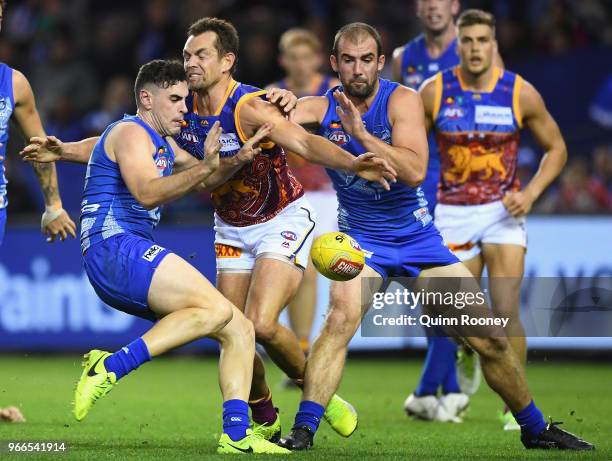 Paul Ahern of the Kangaroos kicks whilst being tackled by Luke Hodge of the Lions during the round 11 AFL match between the North Melbourne Kangaroos...