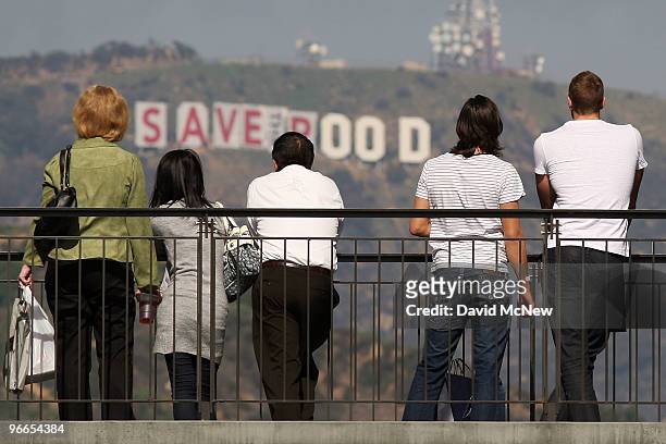 Visitors to the Hollywood and Highland complex take in the view as activists continue covering the iconic 450-foot-long Hollywood sign with banners...