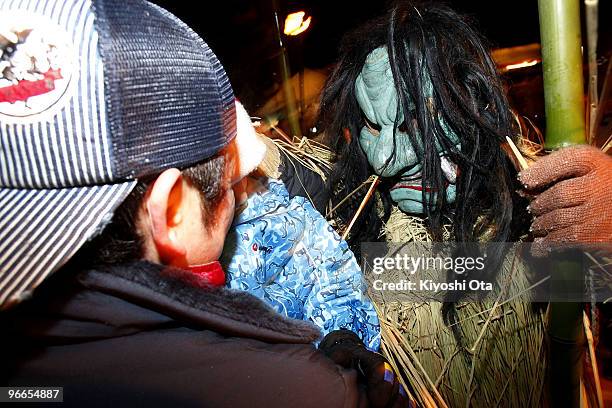 Man dressed in straw clothes and an orge mask as Namahage, or a mountain demon, scares a child during the Namahage Sedo Festival at Shinzan Shrine on...