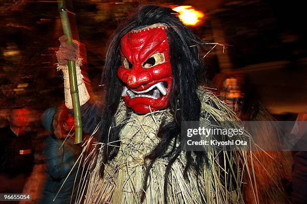 Man dressed in straw clothes and an orge mask as Namahage, or a mountain demon, marches through the grounds of the shrine during the Namahage Sedo...