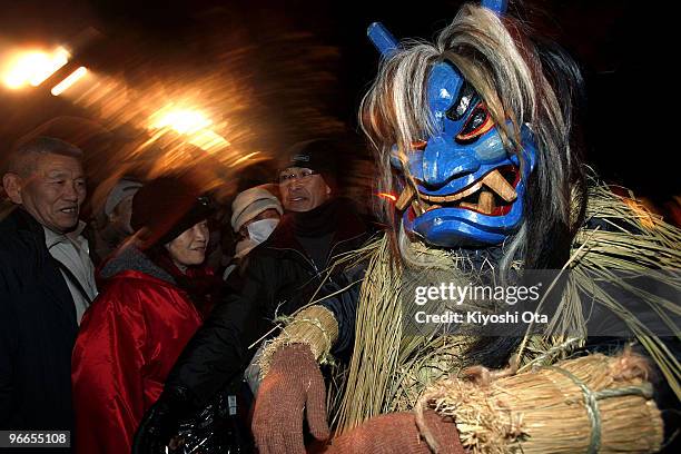 Man dressed in straw clothes and an orge mask as Namahage, or a mountain demon, marches through the grounds of the shrine during the Namahage Sedo...