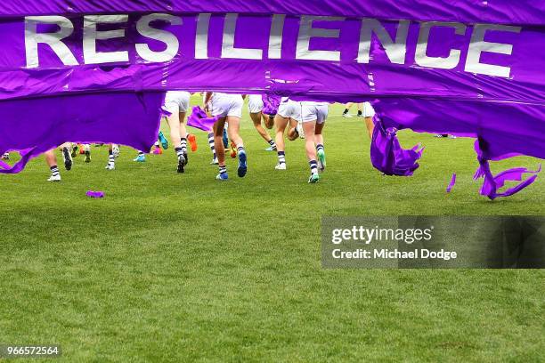 Dockers players break through their banner during the round 11 AFL match between the Collingwood Magpies and the Fremantle Dockers at Melbourne...