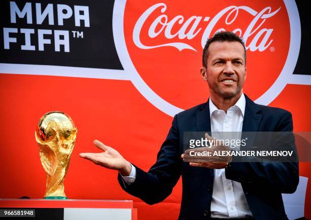 German football player and winner of 1990's world title Lothar Matthaeus presents the FIFA World Cup football trophy during a ceremony to mark the...