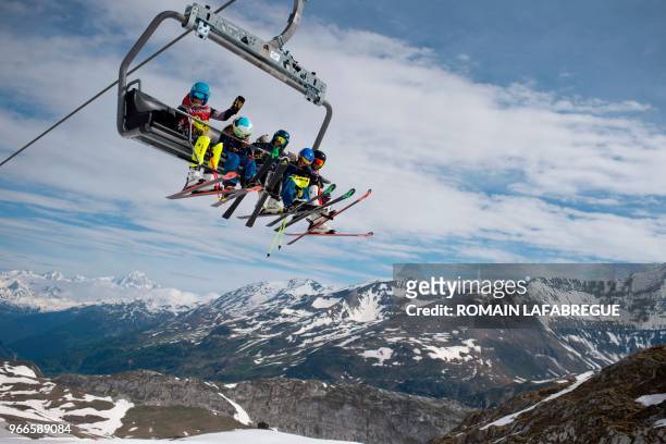 Skiers sit on a ski lift to get to the top of the skiing piste on the opening day of the summer ski season of Val D'Isere resort on June 3 in Val...