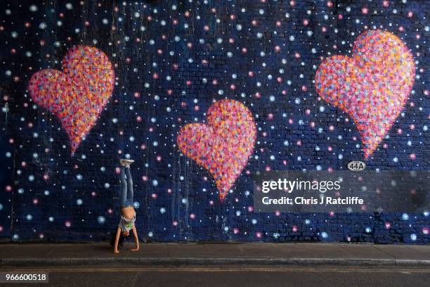 Young girl plays in front of a mural in a tunnel near Borough Market which was painted by graffiti artist James Cochran, also known as Jimmy C, and...