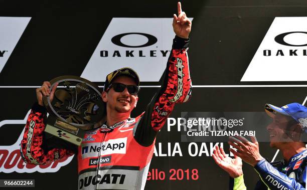 Ducati Team's Spanish rider Jorge Lorenzo celebrates on the podium next to third placed Movistar Yamaha's Italian rider Valentino Rossi after he won...