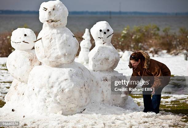 Woman adds a tiny snowman to a snowman family February 13, 2010 during a rare snow storm in Mt Pleasant, South Carolina. About three inches of snow...