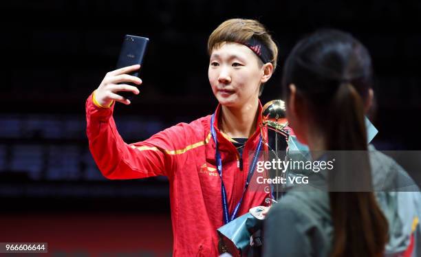 Wang Manyu of China takes a selfie with her trophy during awarding ceremony after winning women's singles final match against Ding Ning of China on...