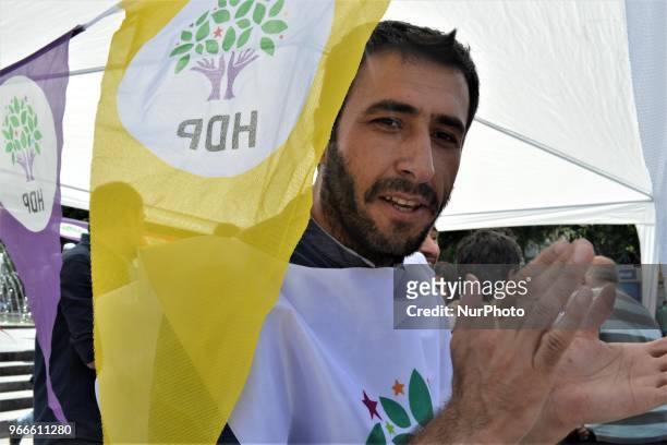 Supporter poses for a photo behind a party flag during the opening of a new election campaign booth of the pro-Kurdish Peoples' Democractic Party for...