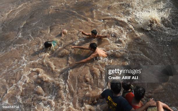 Pakistani people swim in a canal during a hot summer day in Lahore, on June 3, 2018.