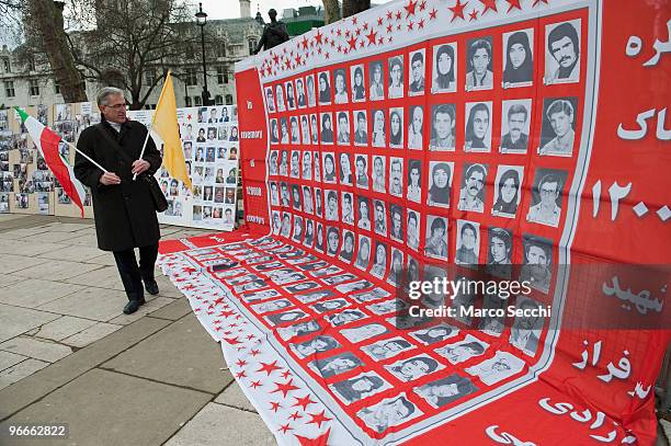 Man holding an Iranian flag walks past a display of photographs of alleged victims of the Iranian regime in Parliament Square on February 13, 2010 in...