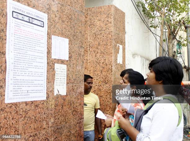 Aspirants look at a poster put up outside the examination center for intructions and guidelines of the exams at Government Girls College, MG road on...