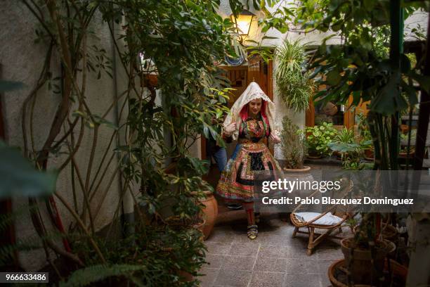 Teresa Moreno 23, wearing the traditional costume of 'Lagarterana' walks past the yard of her house before the start of the Corpus Christi procession...