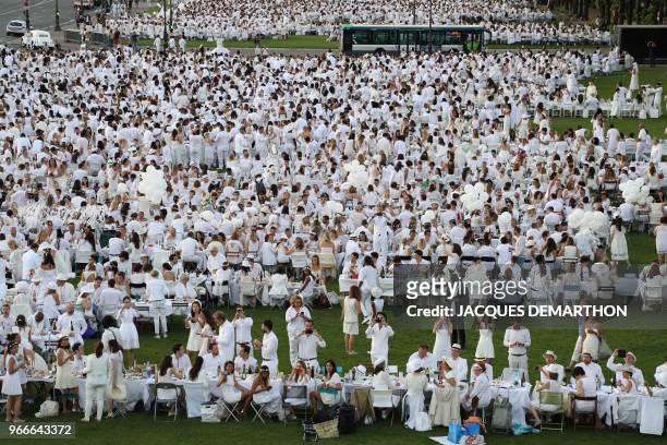 People dressed in white gather for a diner during the 30th edition of the "Diner en Blanc" event on the Invalides esplanade in Paris on June 3, 2018....