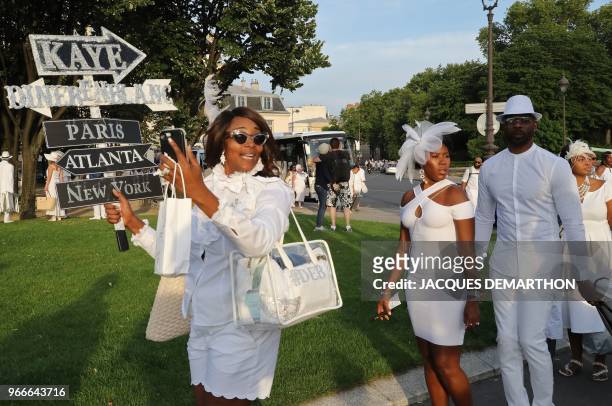 People dressed in white arrive for a diner during the 30th edition of the "Diner en Blanc" event on the Invalides esplanade in Paris on June 3, 2018....