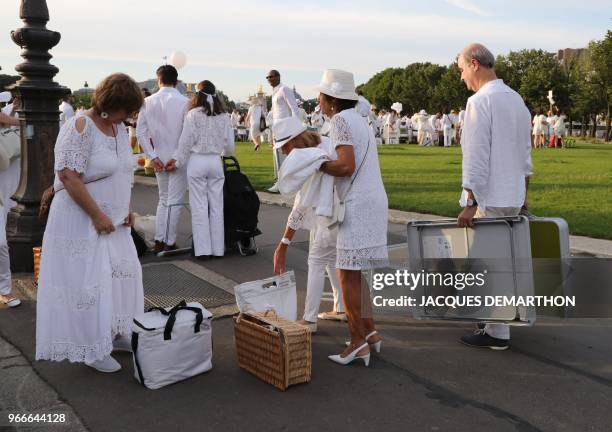 People dressed in white arrive for a diner during the 30th edition of the "Diner en Blanc" event on the Invalides esplanade in Paris on June 3, 2018....