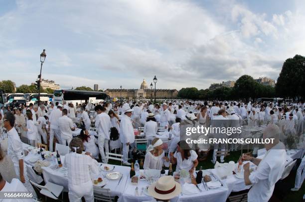 People dressed in white share a diner during the 30th edition of the "Diner en Blanc" event on the Invalides esplanade in Paris on June 3, 2018. -...