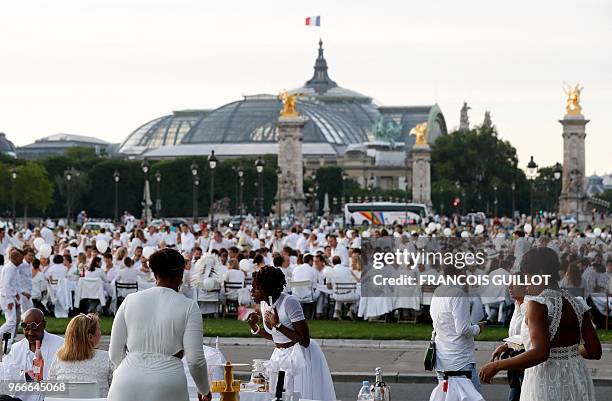 People dressed in white share a diner during the 30th edition of the "Diner en Blanc" event on the Invalides esplanade in Paris on June 3, 2018 with...