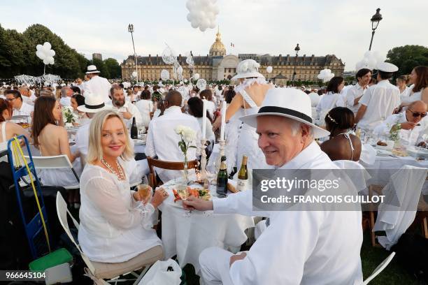 People dressed in white share a diner during the 30th edition of the "Diner en Blanc" event on the Invalides esplanade in Paris on June 3, 2018 with...