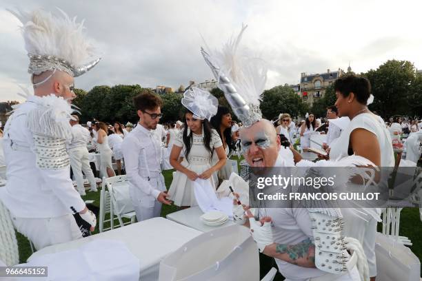 People dressed in white share a diner during the 30th edition of the "Diner en Blanc" event on the Invalides esplanade in Paris on June 3, 2018 with...