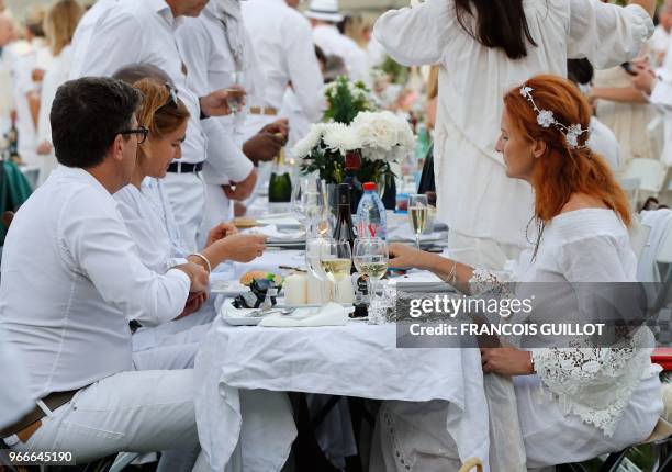 People dressed in white share a diner during the 30th edition of the "Diner en Blanc" event on the Invalides esplanade in Paris on June 3, 2018 with...