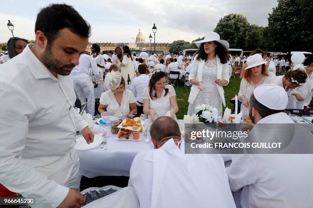 People dressed in white share a diner during the 30th edition of the "Diner en Blanc" event on the Invalides esplanade in Paris on June 3, 2018 with...