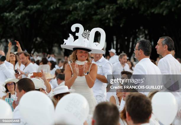 Woman dressed in white and wearing a hat with the number 30 applauds during the 30th edition of the "Diner en Blanc" event on the Invalides esplanade...